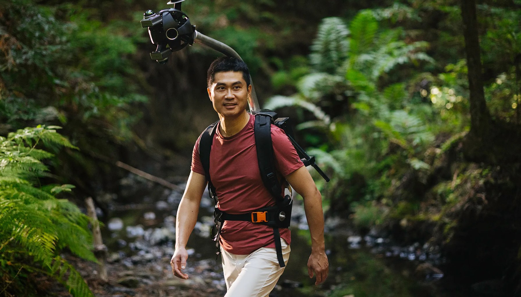 Man hiking in a forest wearing Odyssey camera pack