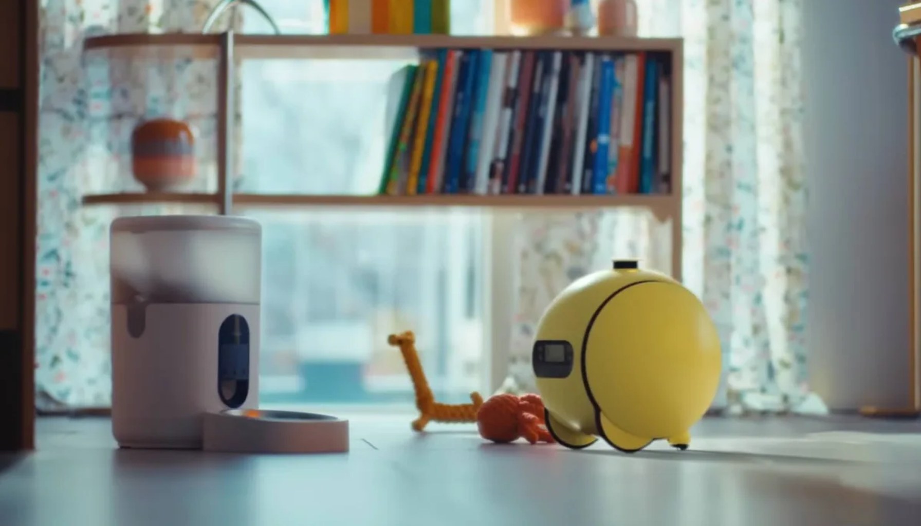 Samsung Ballie robot in a room next to a dog feeder.