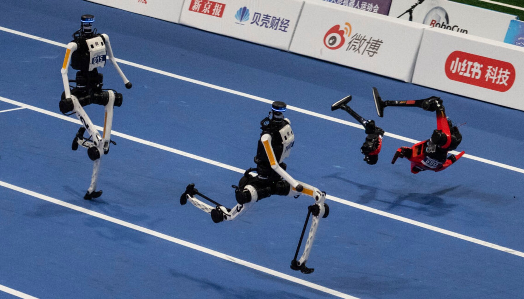 An Honor humanoid robot breaks into pieces as it runs next to two Tian Gong Ultras, center and left, in the second heat of the large robot category of the 100 meter at the 2nd World Robot Games at National Speed Skating Oval on August 25, 2026 in Beijing, China.