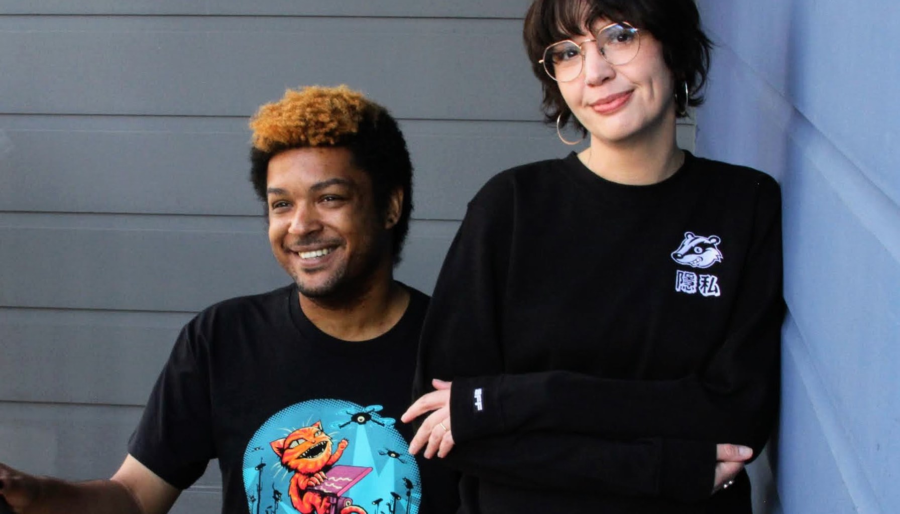 A person wears an EFF Claw Back member t-shirt on the left. A person on the right wears a black sweatshirt with the Privacy Badger mascot on the chest.